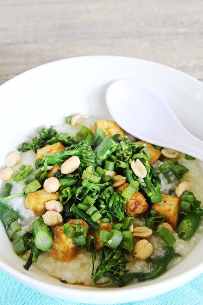 a big bowl of gluten-free and vegan congee with broccoli, scallions, tofu and peanuts