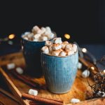 Hot chocolate with marshmallows and cinnamon in blue ceramic cups on a table.