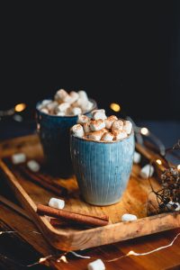 Hot chocolate with marshmallows and cinnamon in blue ceramic cups on a table.